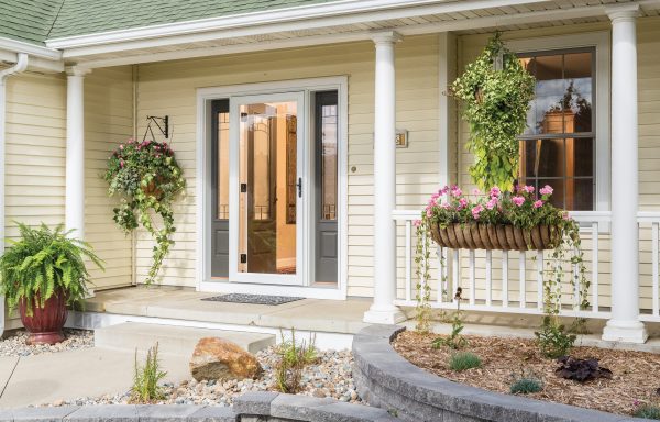 white storm door on a house with light yellow vinyl siding